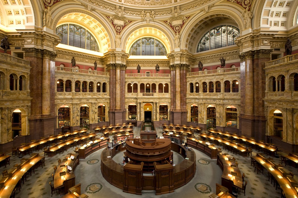 Readers working at long tables in a grand public library reading room